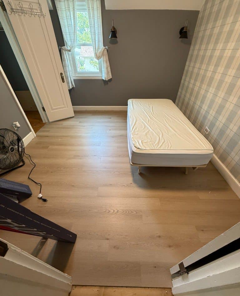 Light oak-look vinyl plank in an upstairs bedroom with a plaid accent wall